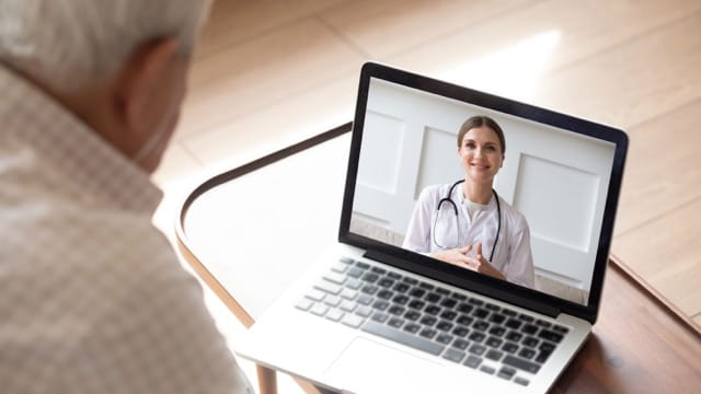 A man uses a laptop to video chat with a provider