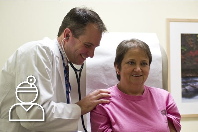 Caregiver using stethoscope on a patient.