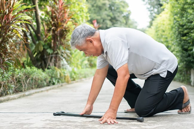 Image of a man with a cane getting up from the ground.