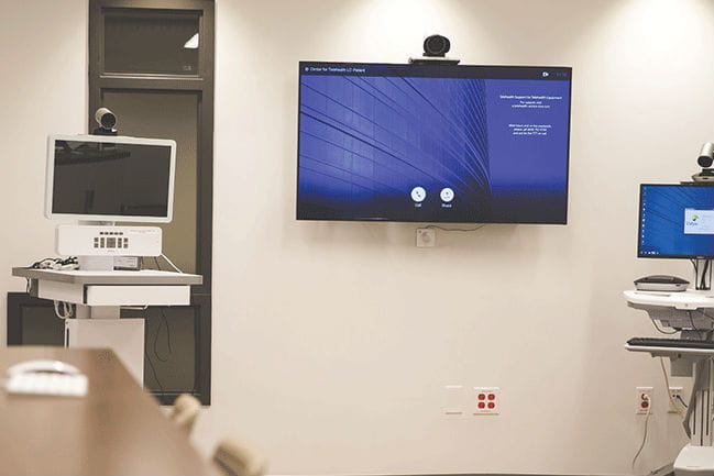 Image of wall with monitor and telehealth  medicine on a cart.