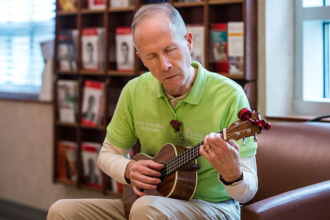 Image of a volunteer playing small guitar.