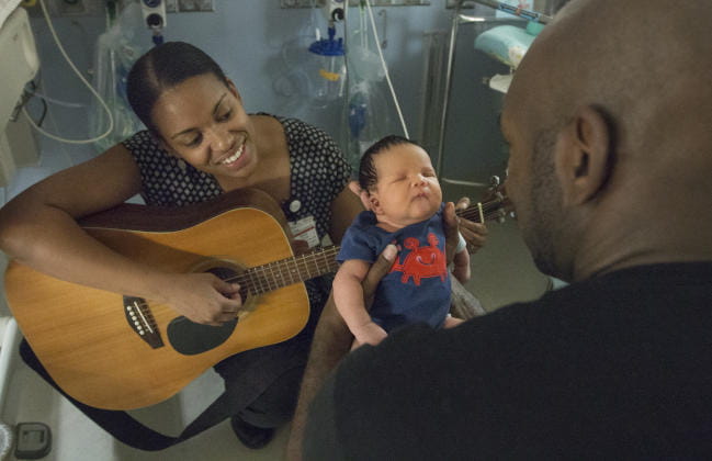 Arts in Healing Music Therapist singing and providing music therapy interventions to pediatric patient, dad, and family at MUSC Children’s Hospital