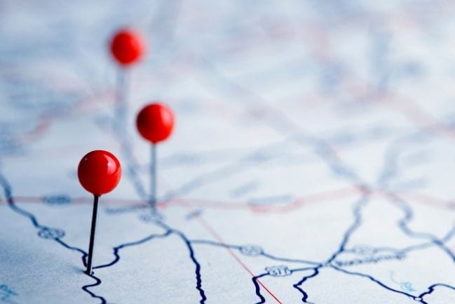 Photo of a map with red pins on it