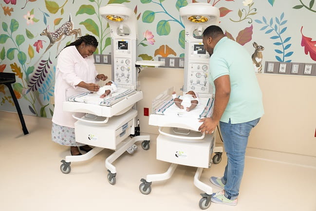 Smiling parents looking down at newborn children.