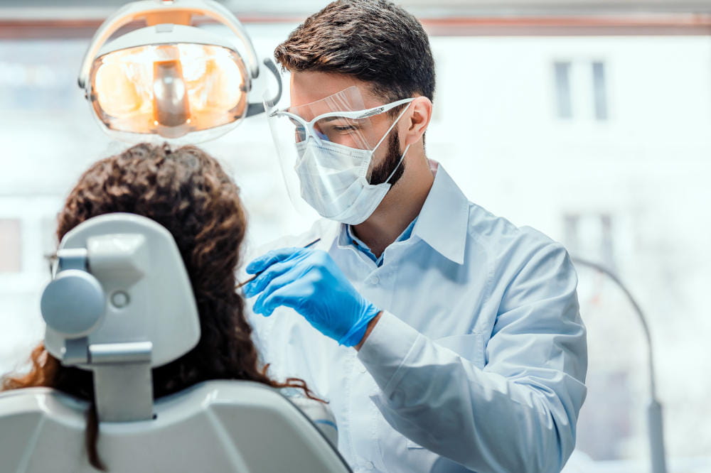 A dental provider examines the teeth of a patient.