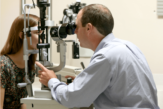 Dr. Magrath performs an eye exam on a patient.