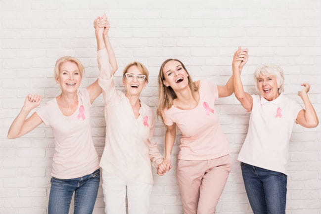 Image of four smiling women raising their arms in celebration.