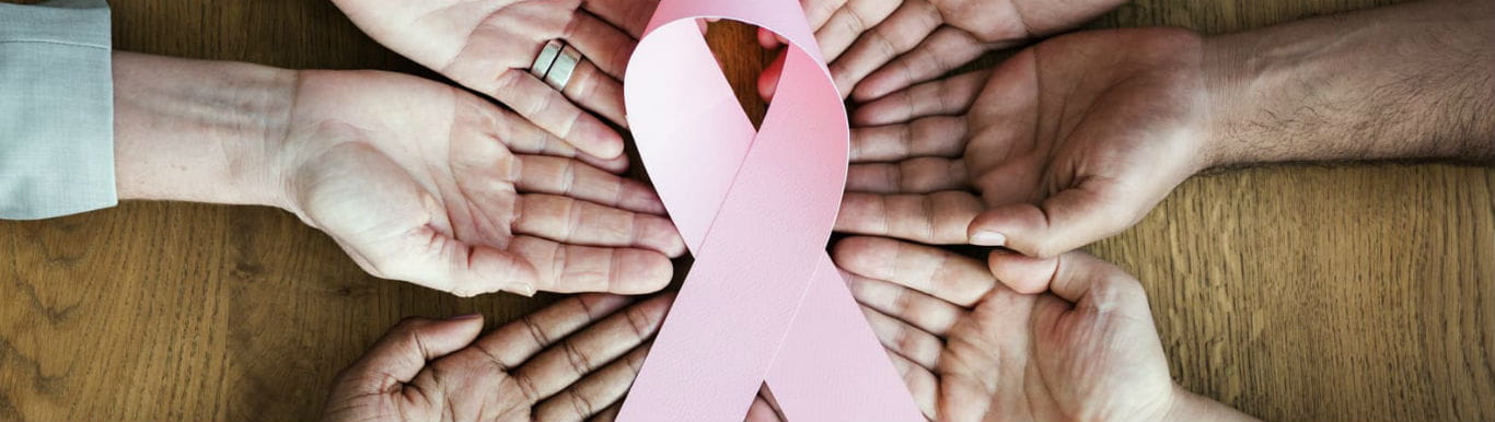 Image of hands surrounding a pink ribbon