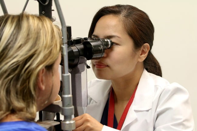 Care team member examining patients eye
