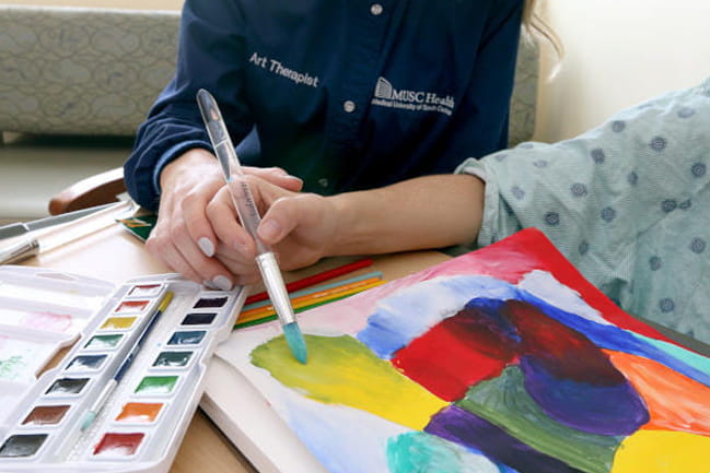 An art therapist with MUSC Health and Wellness Institute helps a patient in art therapy. 
