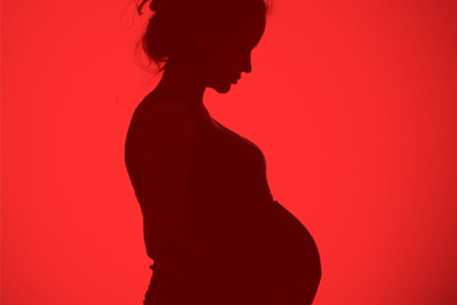 Dark silhouette of pregnant woman over a red background