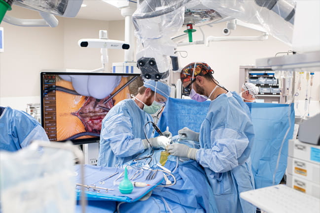 Surgeons performing surgery and a large screen view of surgical site 