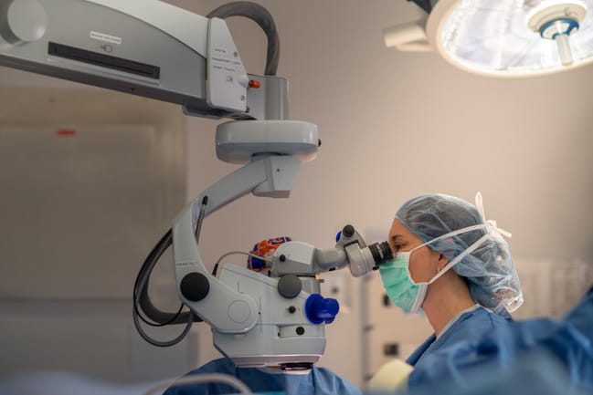 A surgeon looks through a magnifier during iris replacement procedure.    