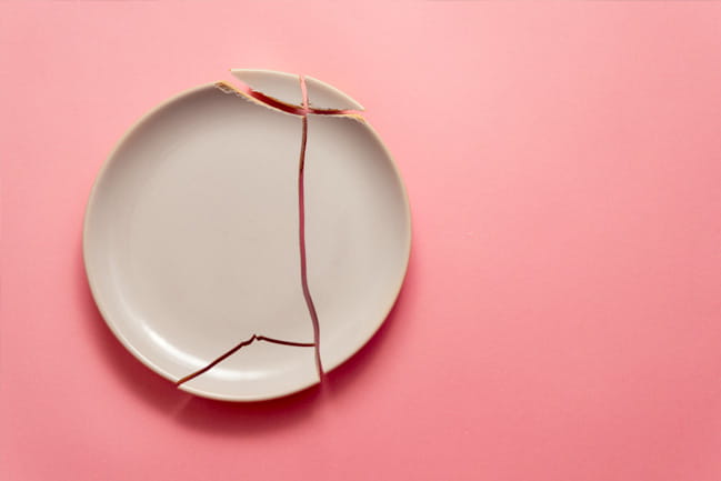 Broken plate over pink background.
