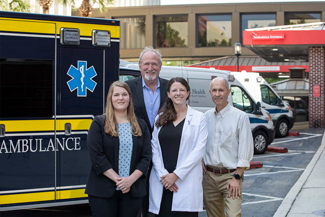 Members of the health care team stand in front of an ambulance