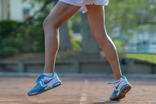 Closeup of female tennis player’s legs in dynamic bouncing action