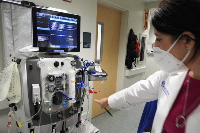Woman standing next to dialysis machine