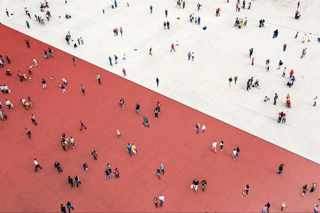 Overhead shot of many pedestrians on a street divided into two colors