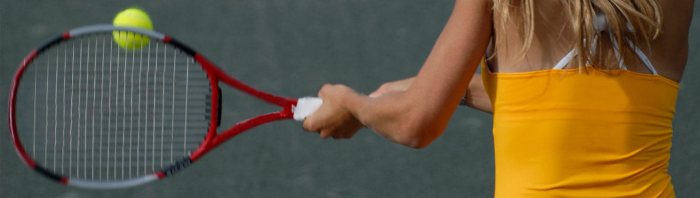 Back of woman swinging tennis racket toward tennis ball