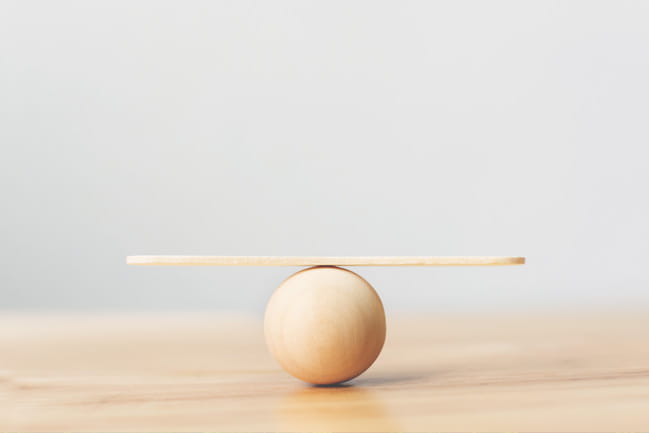 A wooden tongue depressor balanced atop a wooden ball