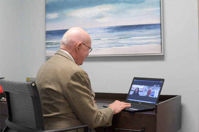 Physician looks at a computer screen for a telehealth appointment.