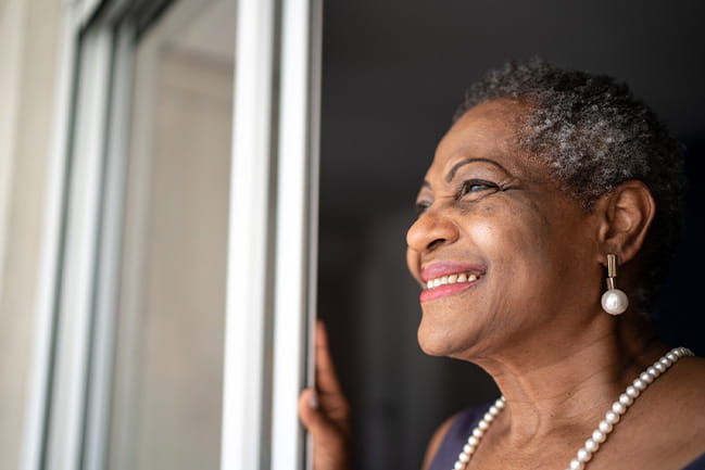 Smiling African American woman gazes out window and into distance