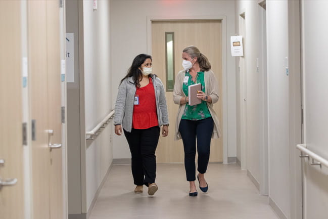 members of the palliative care team discuss their patients in a hallway.