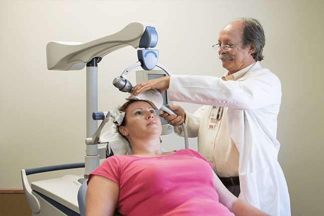 Physician applying magnetic stimulation apparatus to patient’s head