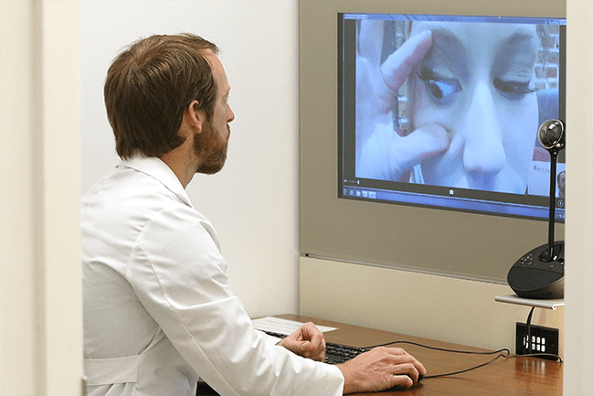 Physician examining woman’s eye on a screen during virtual visit
