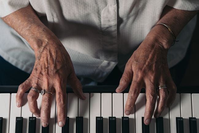 Hands of a senior woman playing piano