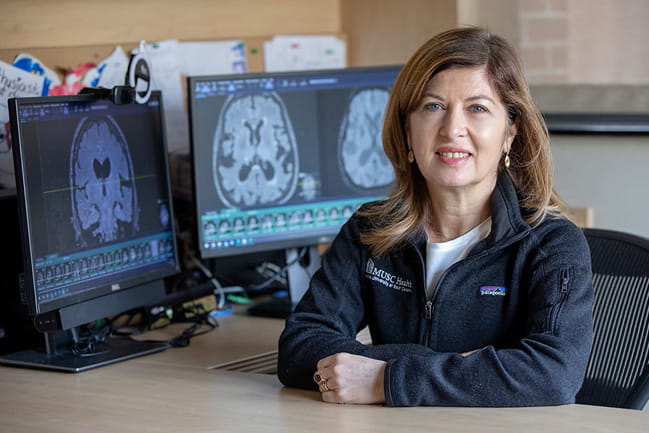 Maria Vittoria Sampinato sits in front of brain scans