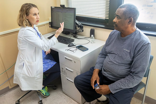 A patient speaks with a physician in a white coat.