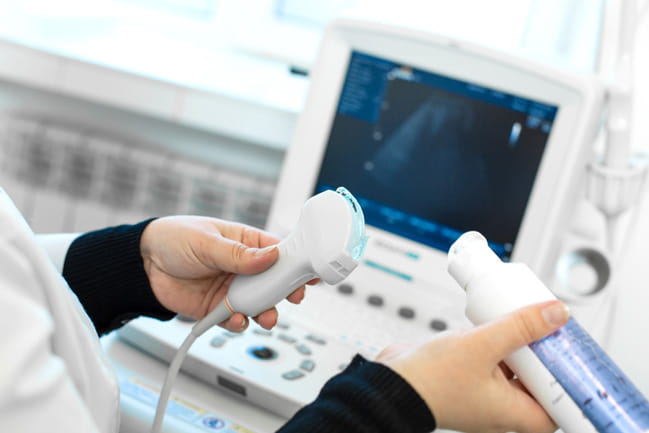 Doctor puts media gel on an ultrasound transducer.