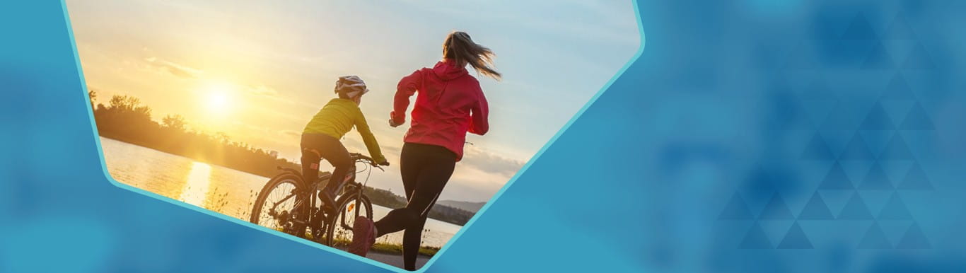 Jogger and cyclist moving in the same direction with a sunrise or sunset in the distance.