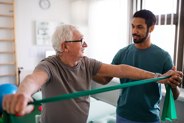 A physical therapist assists a patient using a resistance band