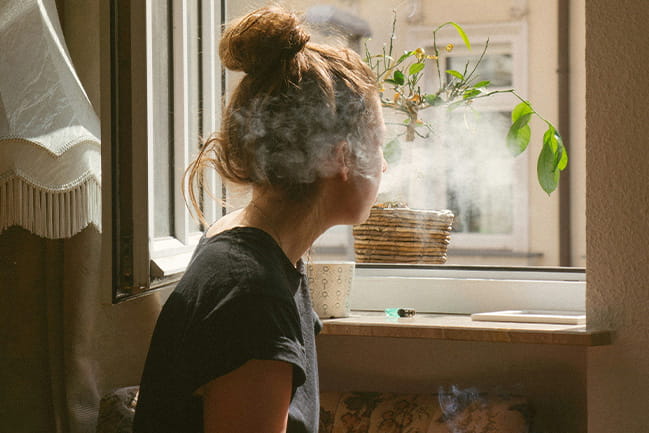 Photo of a person smoking and looking out of window