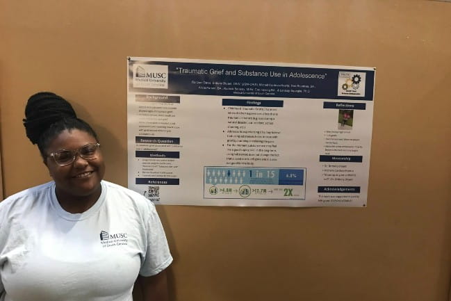 Ambassador Ra’Quel Davis proudly showing off her research poster on Graduation Day.