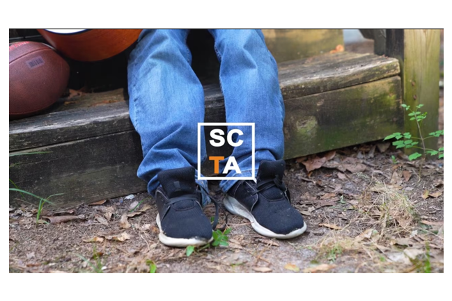 A child's shoes with the SCTA logo overlaid on the image.