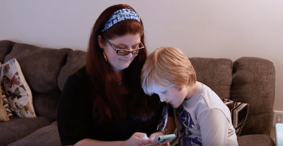 Mother and son looking at teleburn app on phone