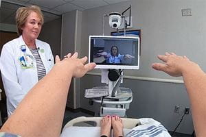 Stroke patient interacting with Doctor via telehealth screen and in-room nurse.