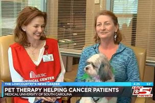 Screen grab from Live5News story showing a volunteer, a patient, and a therapy dog. The chyron on the image reads: Pet therapy helping cancer patients, Medical University of South Carolina