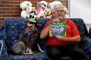 Don reading a book with MUSC Pet Therapy dog, Reba.