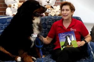 Liz reading a book with MUSC pet therapy dog, Martel.