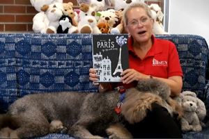 Terri reading a book with MUSC Pet Therapy dog, Harry.