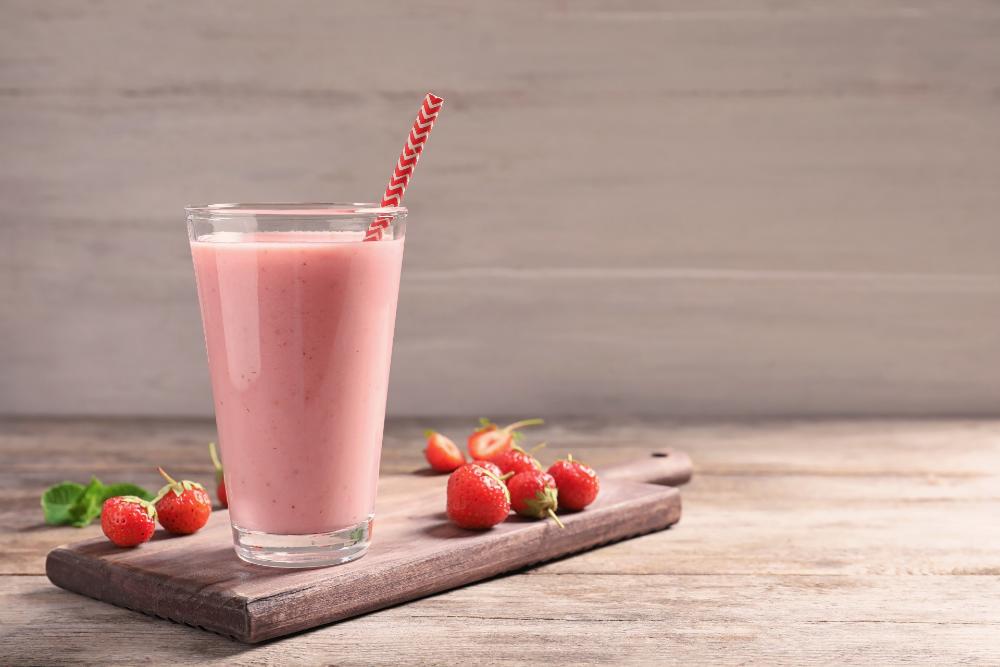 A strawberry smoothie in a glass on a wooden table