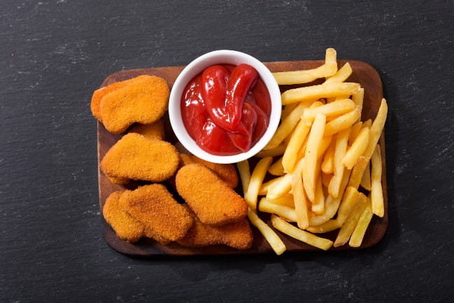 Chicken nuggets, fries, and ketchup on a tray.