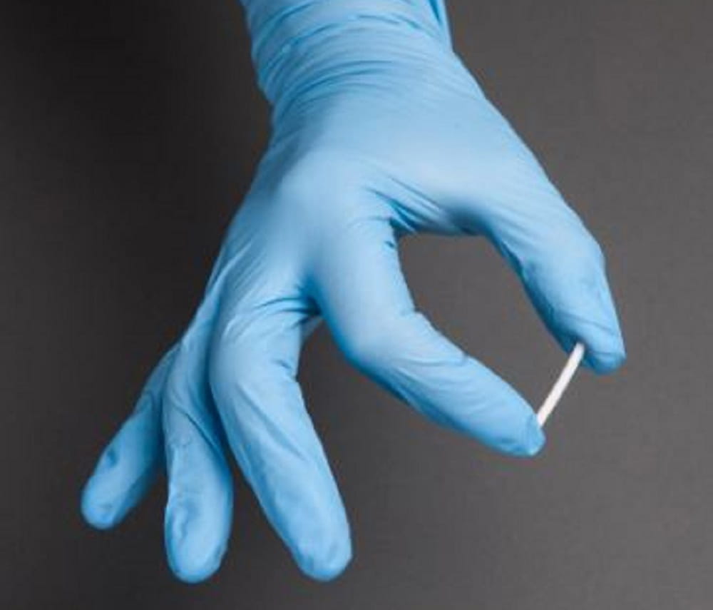 image of gloved hand holding a small white stick-like implant