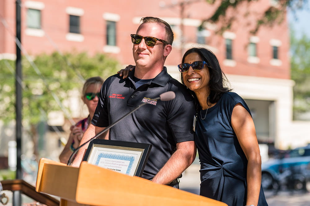 two people stand at a podium and smile 