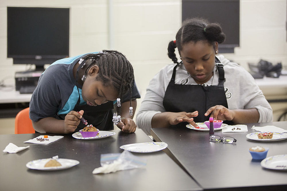 Zy’Karia Walkins and Janae Peeples decorate zucchini muffins.