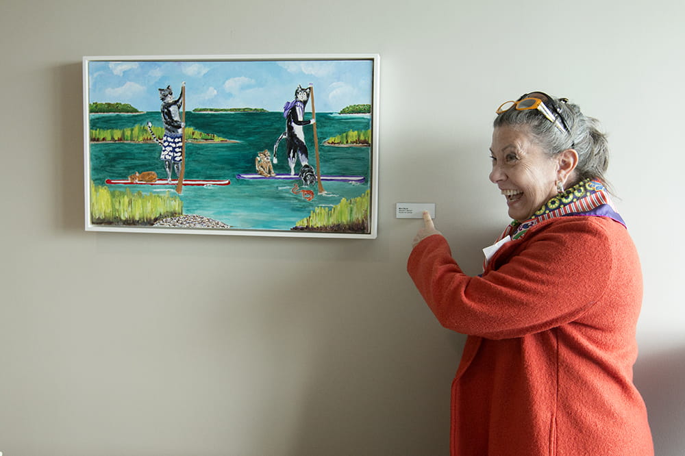 artist Mimi Wood points with glee at the nameplate by her artwork